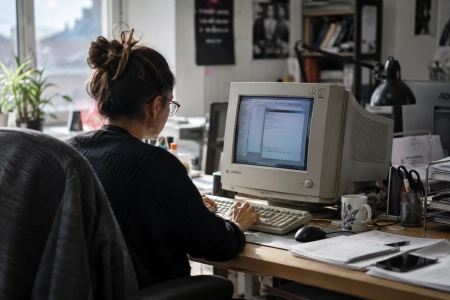 Collaboratrice utilisant un ancien ordinateur dans un environnement de travail contemporain