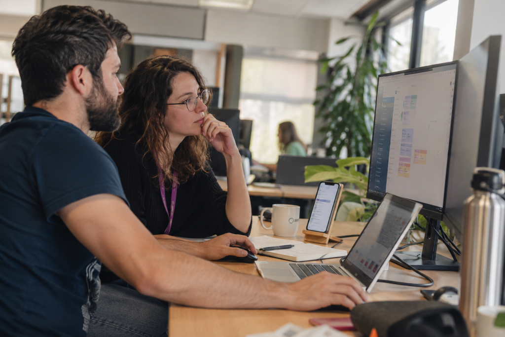 Deux collaborateurs analysant une application existante sur un ordinateur portable et un écran